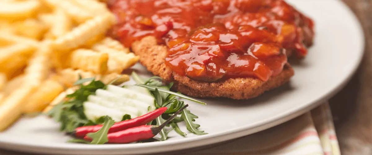 Paniertes Schnitzel mit Tomatensauce, Rucola und Chilischoten