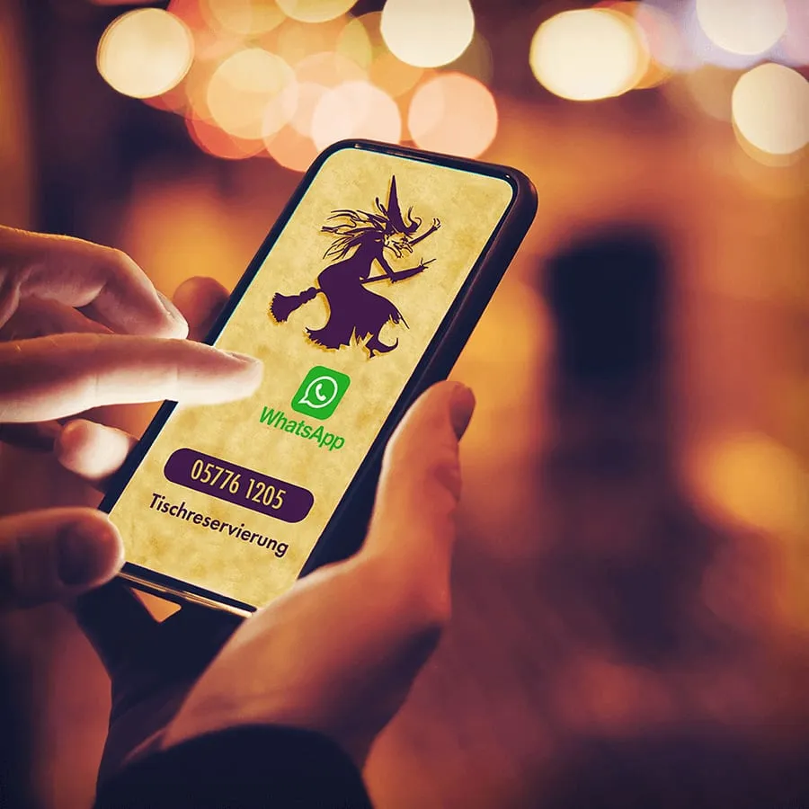 Eine Hand hält ein Handy mit dem WhatsApp-Kontakt des Speukenkieker und der Telefonnummer für Tischreservierungen